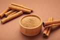 Cinnamon sticks and powder in wooden bowl on brown background Royalty Free Stock Photo