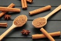 Cinnamon sticks and powder in wooden spoon on black wooden background Royalty Free Stock Photo