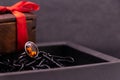 Cinnamon stone ring in brown box on black background and wooden box with red ribbon. Stone ring concept