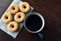 Cinnamon sugar donuts on parchment paper with a cup of coffee on wood table.