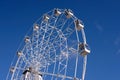 Circle ferris wheel from white metal construction with many rotating cabins over bright blue cloudless sky on sunny day Royalty Free Stock Photo