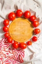 A circle lined with ripe red tomatoes around a wooden cutting board. Vertical photo.