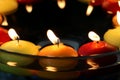 Circle of many candles in colors: yellow and orange red Close-up image. Floating above water. In a bowl. celebration.