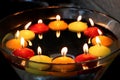 Circle of many candles in colors: yellow and orange red. Floating above water. In a bowl. celebration.