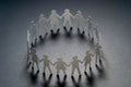 Circle of paper people holding hands on dark surface. Community, union concept. Society and support. Royalty Free Stock Photo