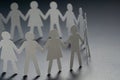 Circle of paper people holding hands on dark surface. Community, union concept. Society and support. Royalty Free Stock Photo