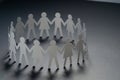 Circle of paper people holding hands on dark surface. Community, union concept. Society and support. Royalty Free Stock Photo