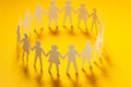 Circle of paper people holding hands on yellow surface. Community, union concept. Society and support. Royalty Free Stock Photo