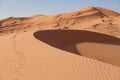 Circle-shaped dune with undulating sand and sand traces in the background large dune with horizontal lines