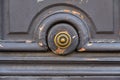 Circle shaped metal doorknob of old shabby wooden door with flaking paint of grey color. Brass doorknob in center of dusty door Royalty Free Stock Photo