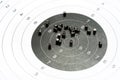 Circle shooting target and lots of metal pellets laying on top, object closeup, detail, nobody. Airgun sports, accessories. Pellet