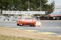 An Orange Porsche 934 being chased by a Rondeau m378 in a classic cars race