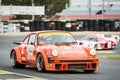 An Orange Porsche 934 being chased by a Rondeau m378 in a classic cars race
