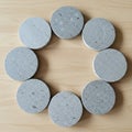 Circular arrangement of eight gray concrete discs on a light wooden surface. Each di Royalty Free Stock Photo