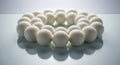 A circular arrangement of small white felt balls on a reflective surface with a light blue background creating a calm and peaceful Royalty Free Stock Photo