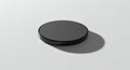 Circular black object with a glossy finish on a light gray background. The object casts a Royalty Free Stock Photo