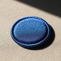 A circular blue fabric button placed on a textured beige surface Royalty Free Stock Photo
