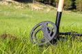 A circular disk of metal detector and shovel on the meadow with green grass
