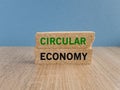 Circular economy symbol. Concept green words Circular economy on brick blocks. Beautiful wooden table blue background. Business