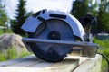 A circular electric saw with a green pen lies on wooden boards