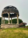 Circular garden gazebo with white pillars and black rounded roof
