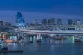 Circular highway leading to the Rainbow Bridge with Cargo and cruise ships moored or sailing in Odaiba Bay of Tokyo