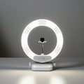 A circular LED ring light with a white plastic body is placed on a flat surface. The light Royalty Free Stock Photo