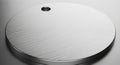 Circular metal disc with a brushed, silver finish. The surface features fine, linear grooves giving Royalty Free Stock Photo