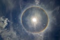 Circular rainbow halo around the sun among blue sky and white clouds Royalty Free Stock Photo