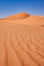 Circular red dune shot from below to photograph the vertical sand streaks of the Rub al Khali desert Royalty Free Stock Photo