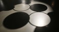Circular shadows and bright light patterns overlap on a dark surface, creating an abstract design. Royalty Free Stock Photo