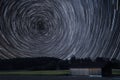Circular star trails over farming filed with sunflowers and wooden barn