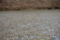 Circular tree bowls in rough irregularly stacked paving. The brown walls of a historic building with a longitudinal canal distract