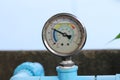 Circular water pressure meter attached to blue PVC water pipe to measure tap water pressure. Royalty Free Stock Photo