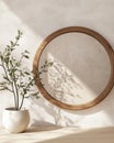 A circular wooden frame on a light wall, with a potted plant casting a shadow next to it Royalty Free Stock Photo