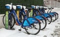 Citibike NYC bike share bicycles docked in their charging stations covered in snow during winter in Brooklyn, New York City.