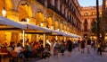 Citizens and tourists stroll and relax in cafe in light of streetlight on Royal square in Barcelona.