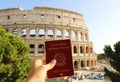 Citizenship concept: hand hold Italian passport in front of Colosseum in Rome