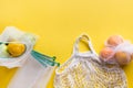 Citrics in reusable eco-friendly mesh bags with on yellow background. Zero waste concept. Ecological shopping. Stop pollution