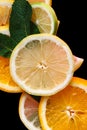 Citrus on a black background. Many slices of lemon, orange, lime and mint leaves lie together. A lot of fruits. Vitamins Royalty Free Stock Photo