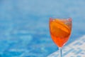 A citrus cocktail stands on the side of a blue pool, copyspace