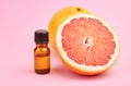 Citrus essential oil in bottle with fresh grapefruit halves on pink background. Royalty Free Stock Photo