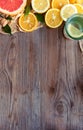 Citrus fresh summer fruits and water glass on brown wooden background, vertical Royalty Free Stock Photo