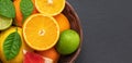 Citrus fruits in a basket on a gray stone background close up. Citrus fruit mix. Orange, lemon and lime with leaves. Banner. Copy Royalty Free Stock Photo