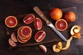 Citrus fruits, blood oranges on a cutting board with a knife on a dark wooden background top view