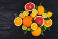 Citrus fruits, half grapefruits, lemons, oranges, limes with green leaves lie on a brown wooden table. view from above Royalty Free Stock Photo