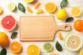 Citrus fruits, leaves and board on wood background Royalty Free Stock Photo