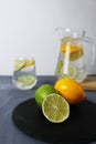 citrus fruits lemon and lime lie on a black tray and lemonade in a cubit glass. Preparation of drinks. Soft drinks Royalty Free Stock Photo