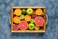 Citrus fruits mix flat lay in wooden tray on blue concrete background Royalty Free Stock Photo