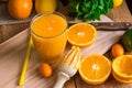 Citrus fruits oranges lemons lime cumquat, fresh mint, reamer, freshly pressed juice in glass on table